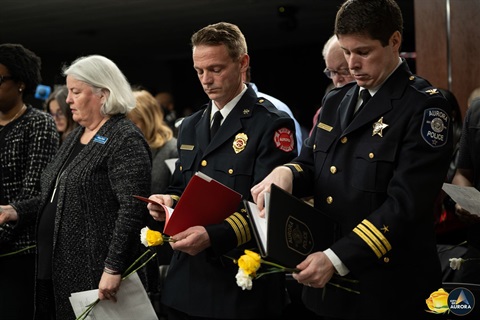 Members gather with heads bowed to pay tribute to the lives lost during the Henry Pratt Tragedy in Aurora.